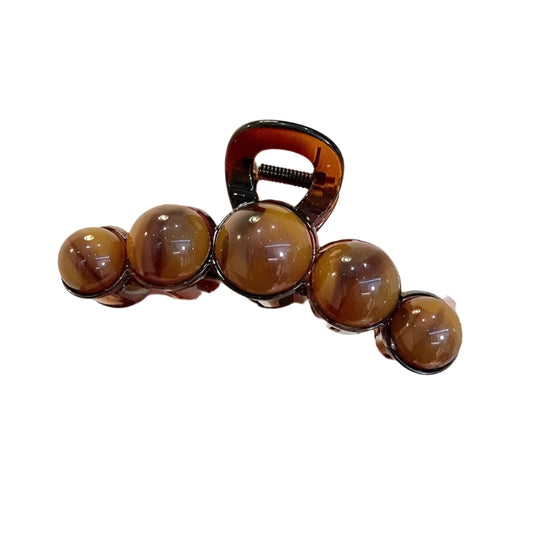 Hand holding a hair clip with brown beads against a neutral background