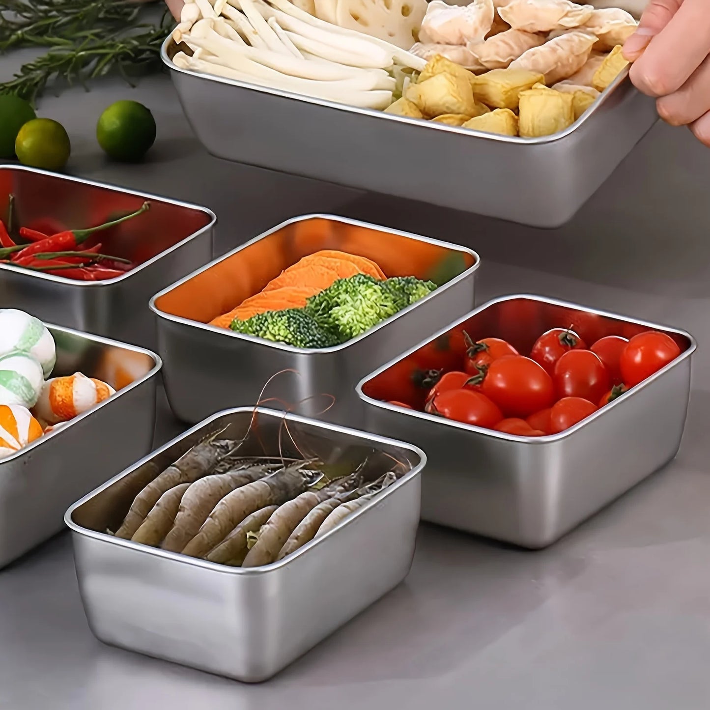 Set of stainless steel food containers with various ingredients on a gray surface