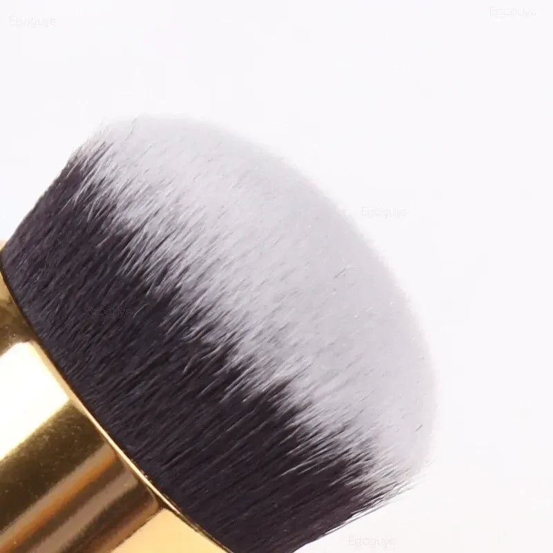 Makeup brush with black bristles and gold handle on a white background
