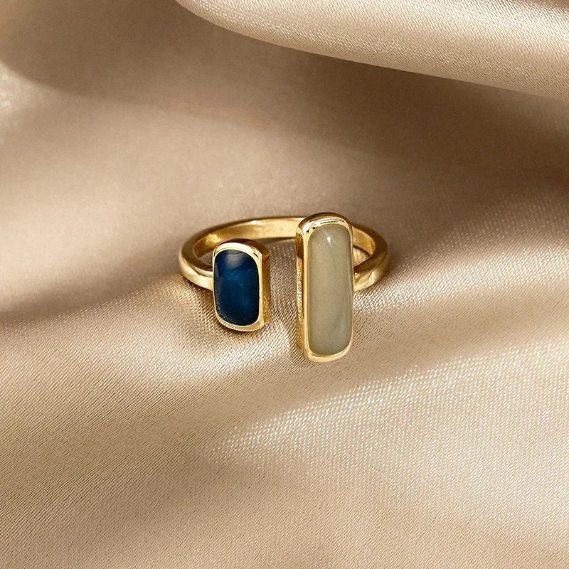Gold ring with blue and white stones on a beige fabric background