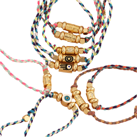 Colorful braided bracelets with gold beads on a beige background
