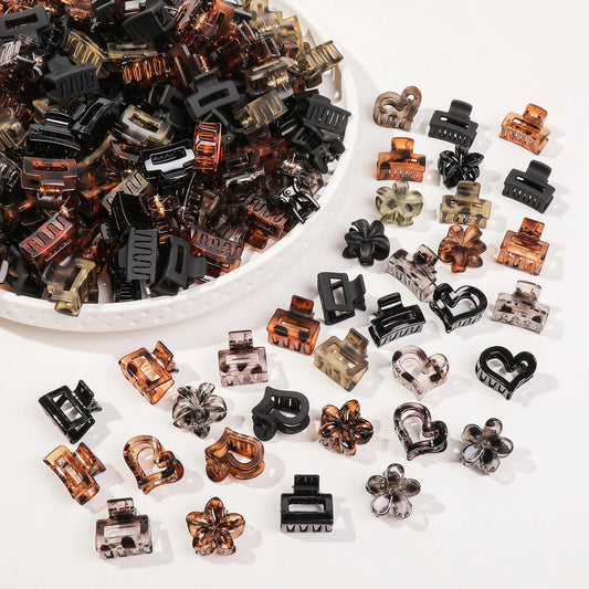Assorted hair clips on a white surface with a bowl of clips in the background.