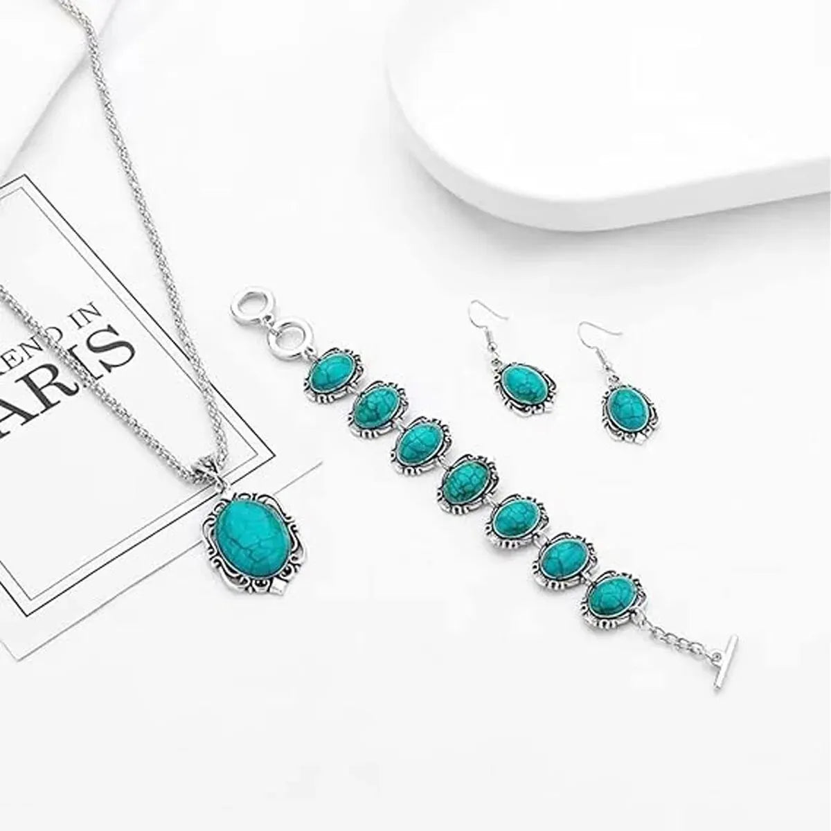 Turquoise jewelry set with necklace, bracelet, and earrings on a white surface.