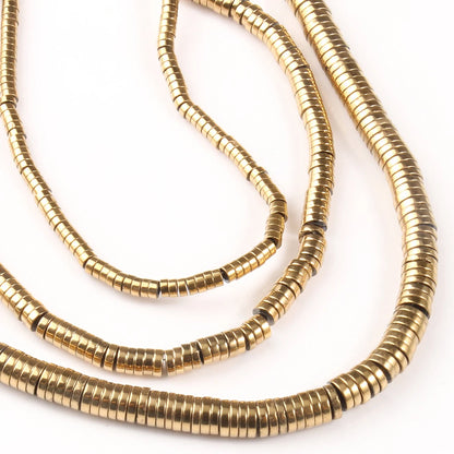 Three gold necklaces with a heishi bead design on a white background