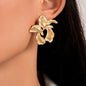 Gold leaf-shaped earrings worn by a person with dark hair.