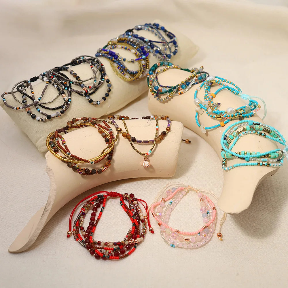 Collection of beaded bracelets on mannequin hands against a neutral background