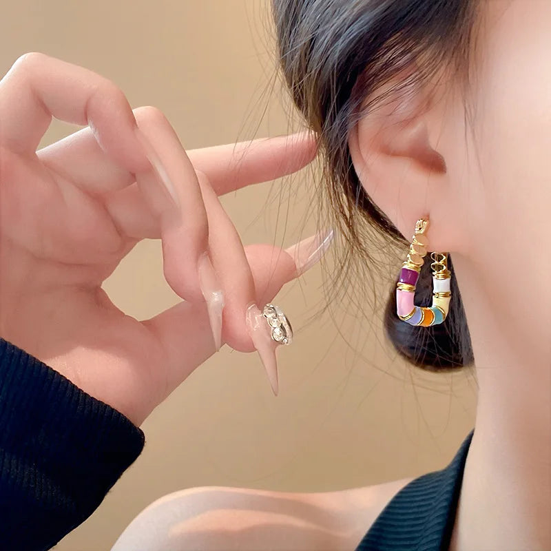 Person wearing colorful hoop earrings with a neutral background