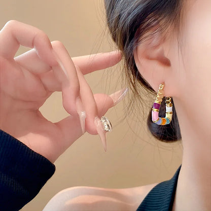 Person wearing colorful hoop earrings with a neutral background
