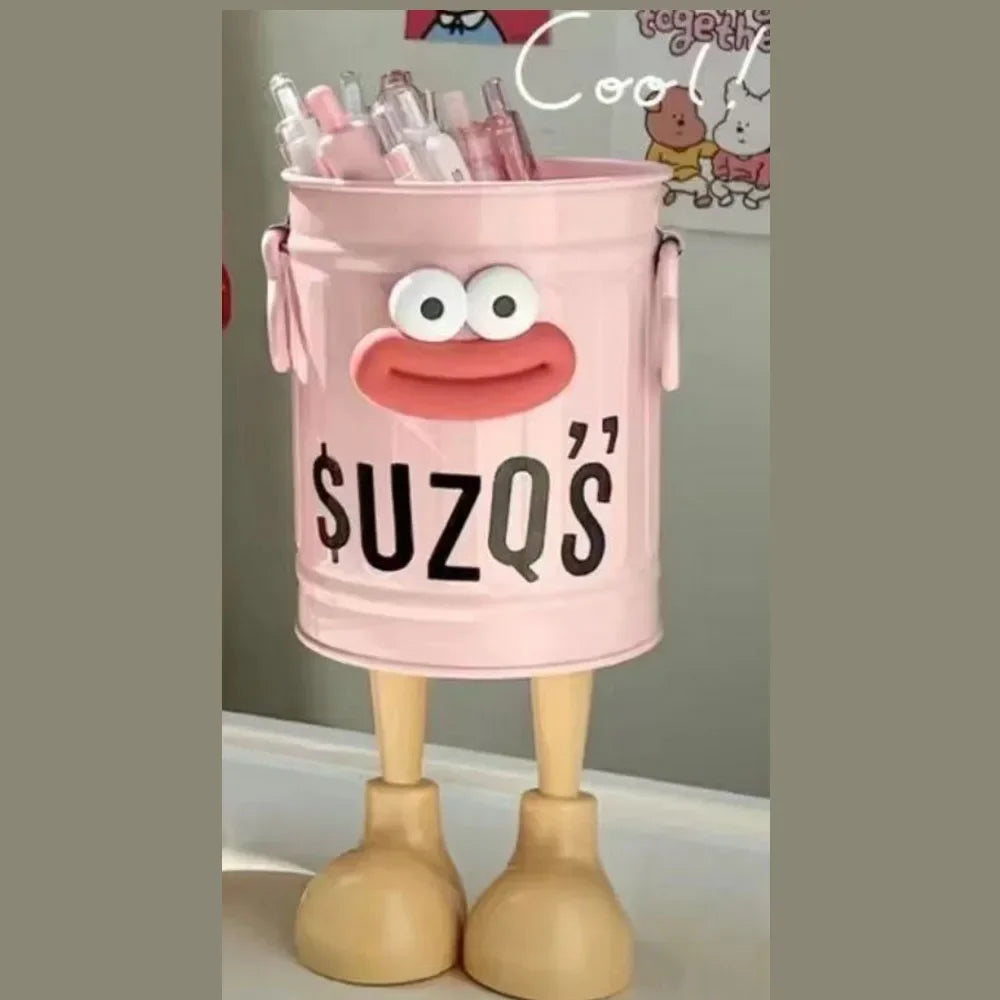 Pink toy bucket with face and 'SUZQ'S' text, filled with small bottles, on a neutral background.