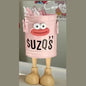 Pink toy bucket with face and 'SUZQ'S' text, filled with small bottles, on a neutral background.