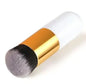 Makeup brush with gold handle and black bristle head on a white background