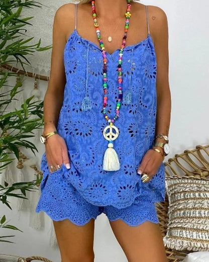 Person wearing a blue lace dress with a colorful necklace against a white wall.