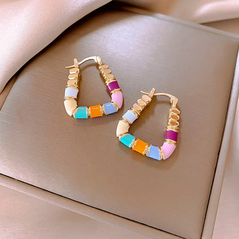 Colorful beaded hoop earrings on a beige surface
