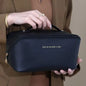 Person holding a black cosmetic bag with 'Rose of Na Man's Land' branding.