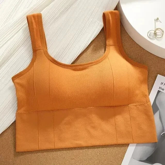 Orange sports bra on a textured surface with a magazine underneath
