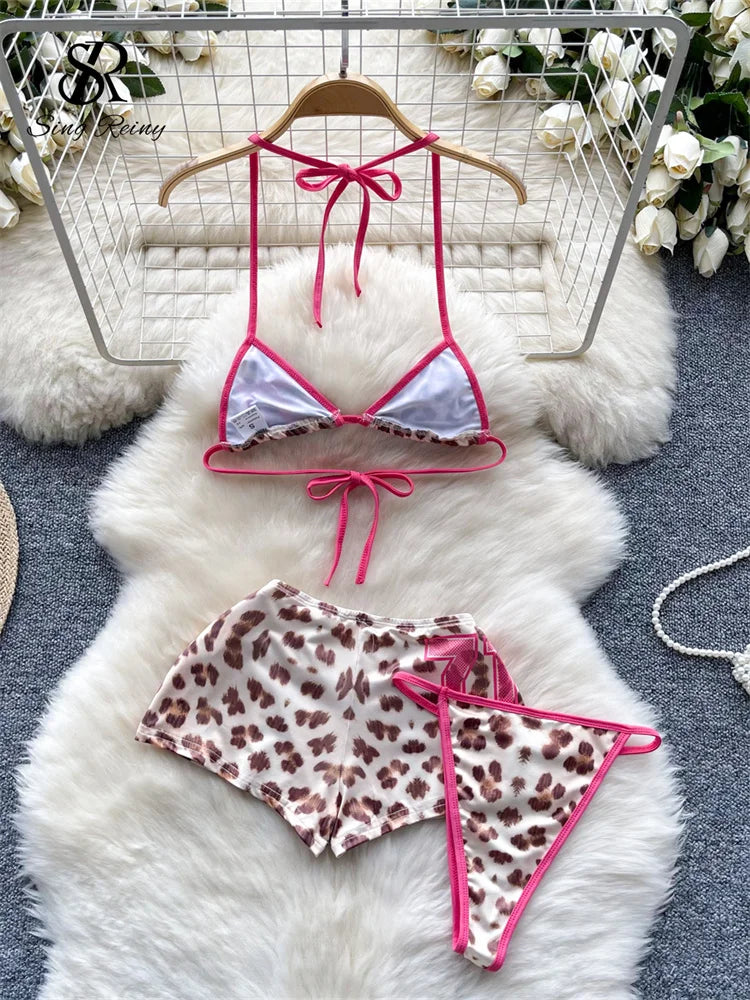 Bikini set with pink straps and leopard print bottom on a white fur surface.