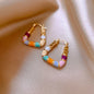 Colorful beaded hoop earrings on a beige fabric background