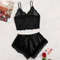 Black lace lingerie set on a light surface with a magazine and rose in the background