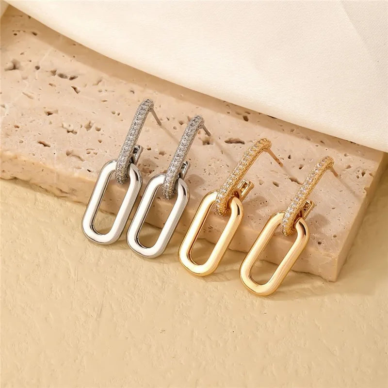 Pair of gold and silver hoop earrings on a textured beige surface