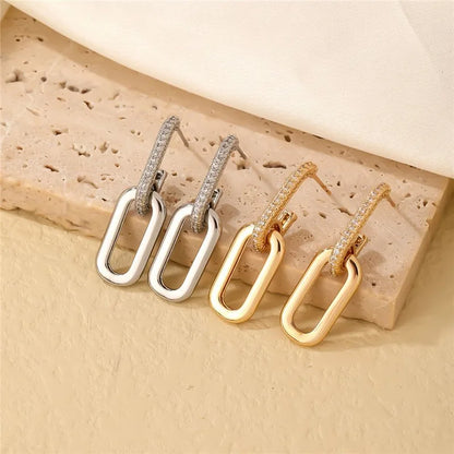 Pair of gold and silver hoop earrings on a textured beige surface