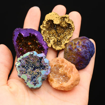 Hand holding five colorful geode-like rocks against a black background