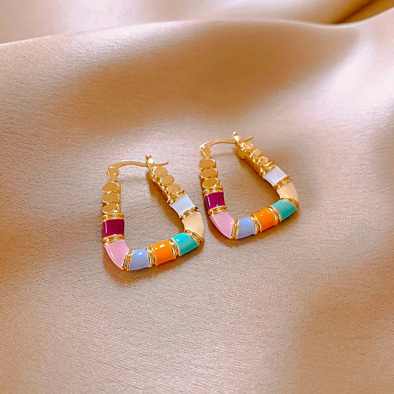Colorful hoop earrings on a beige fabric background
