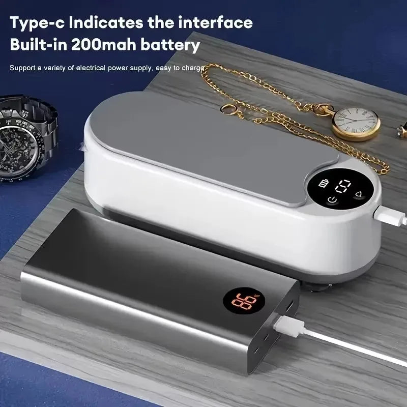 Portable power bank with digital display on a wooden surface with jewelry and a watch.