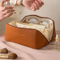 Brown cosmetic bag with makeup items on a beige background