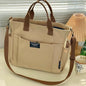 Beige tote bag with brown handles and strap on a light surface.