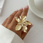 Gold floral ring on a hand with a light background