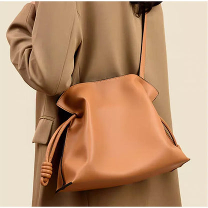 Brown leather handbag worn over one shoulder against a neutral background