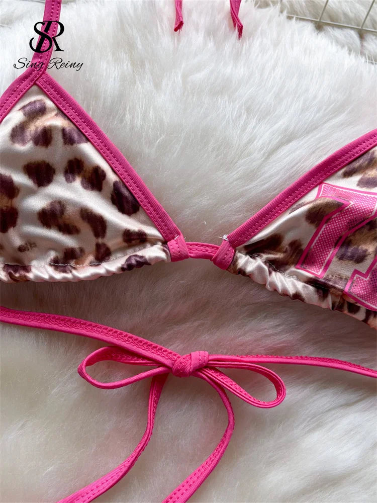 Leopard print bikini top with pink straps on a white fur background, featuring the brand 'Sasha Reign'.