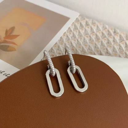 Silver earrings on a brown surface with a blurred background