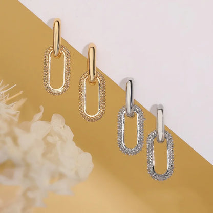 Gold and silver chain-style earrings on a yellow and white background
