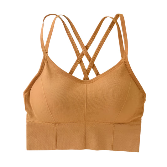 Mustard yellow sports bra with criss-cross straps on a white surface.