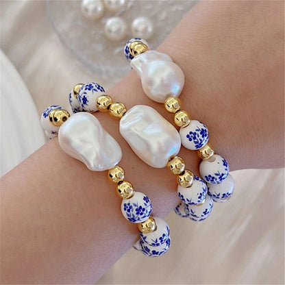 Bracelet with pearls, gold beads, and blue floral beads on a wrist.
