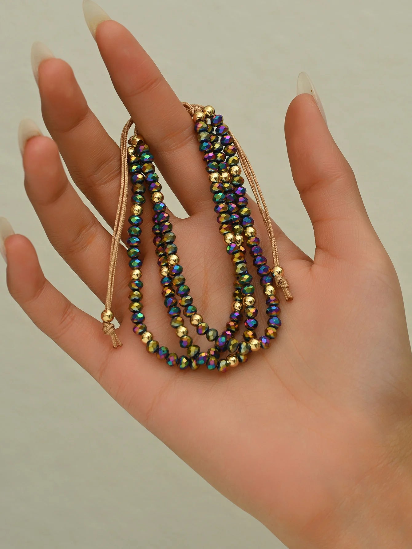 Hand holding three beaded necklaces with a neutral background