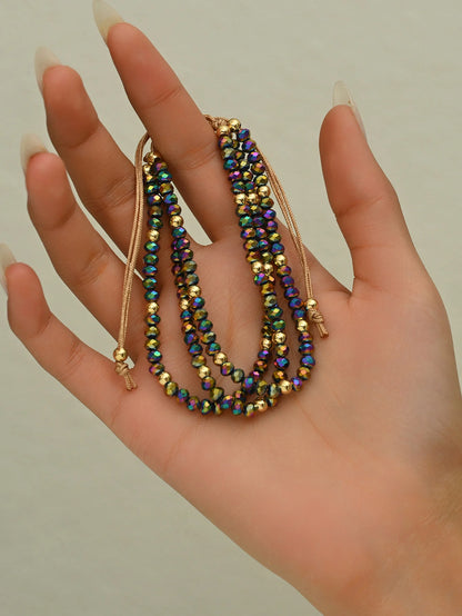 Hand holding three beaded necklaces with a neutral background