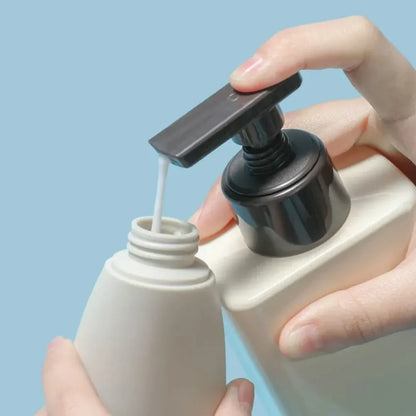Hand using a pump to dispense liquid from a bottle against a light blue background
