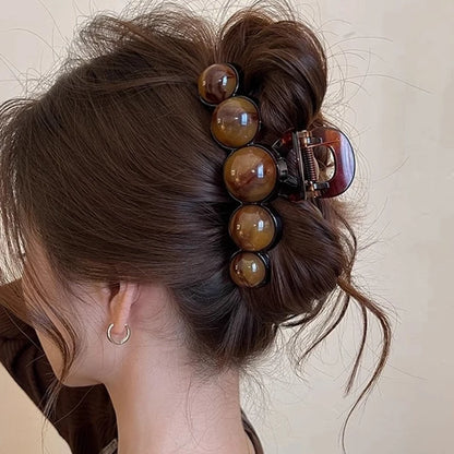 Close-up of a hair bun with decorative hair clips on a neutral background
