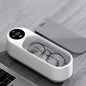 White electronic device with a digital display and glasses inside, on a wooden surface.