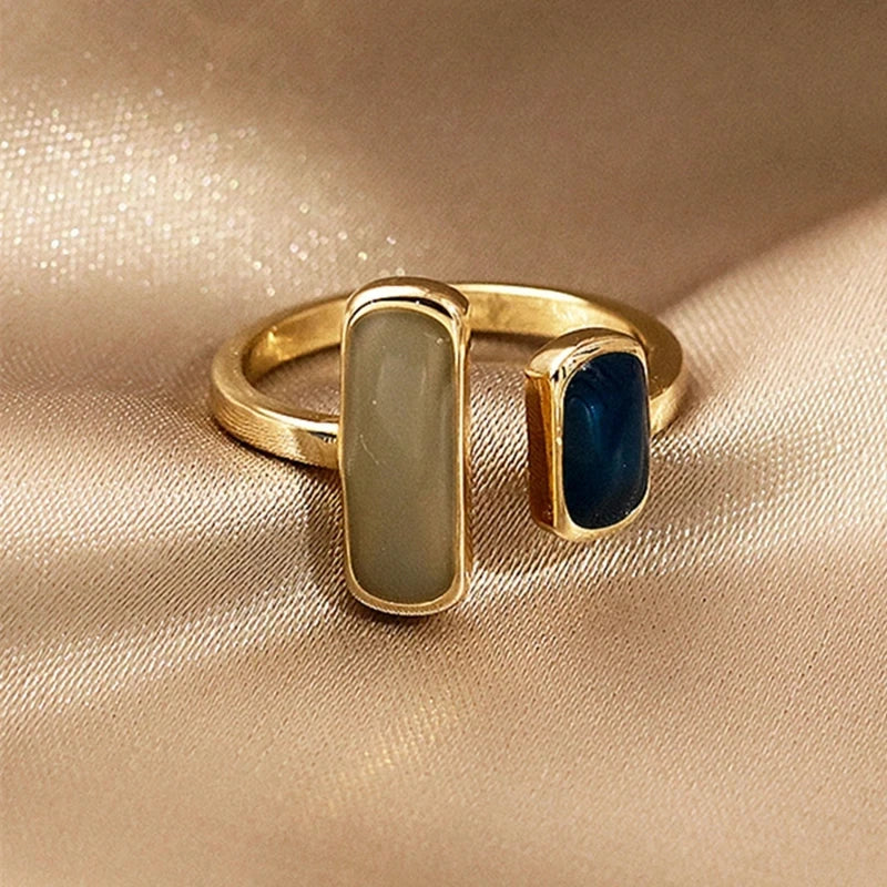 Gold ring with two gemstones on a beige fabric background