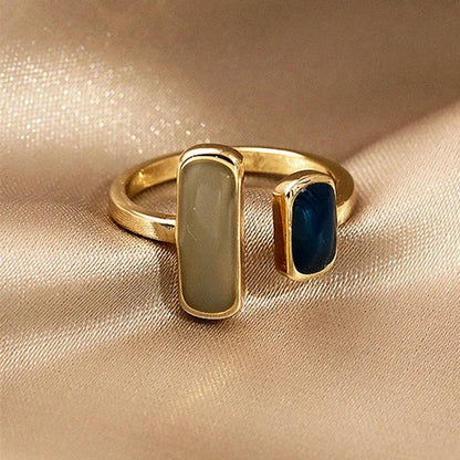 Gold ring with two gemstones on a beige fabric background