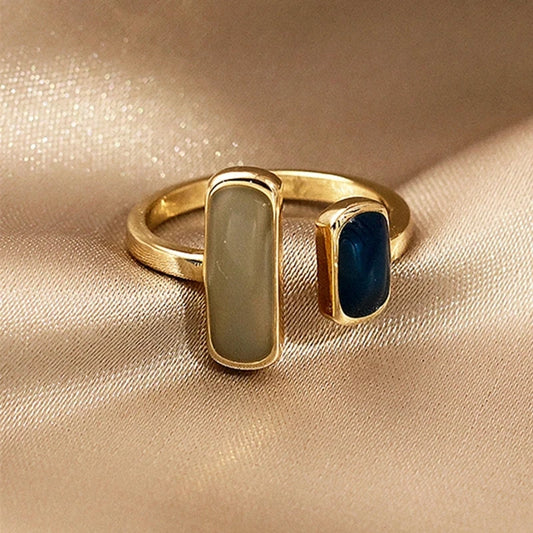 Gold ring with two gemstones on a beige fabric background
