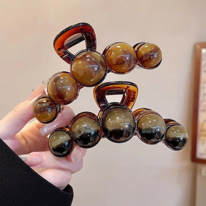 Hair clip with brown beads held by a hand against a neutral background