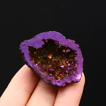 Purple geode held in a hand against a black background
