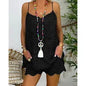 Person wearing a black sleeveless top and shorts with colorful necklaces, standing indoors.