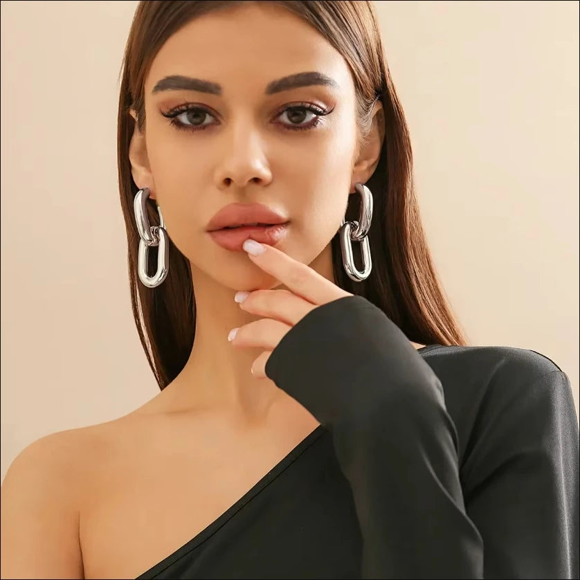 Woman wearing large hoop earrings with a neutral background