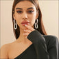 Woman wearing large hoop earrings with a neutral background