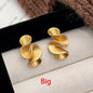 Gold spiral earrings on a textured surface with 'Big' text.